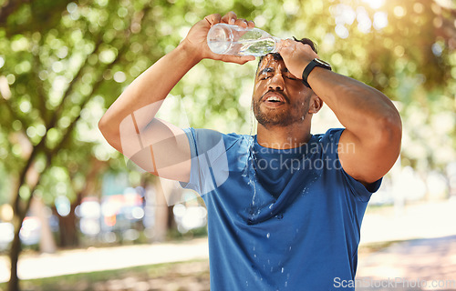 Image of Fitness, outdoor and a man pouring water on face after exercise, training or running at a park. Tired Indian male athlete in nature for workout, run and break or cooling down with a splash in summer