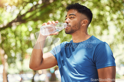 Image of Fitness, man or runner drinking water outdoor for exercise, training or running at a park. Indian male athlete in nature for a workout, run and break to drink from a bottle for health and wellness