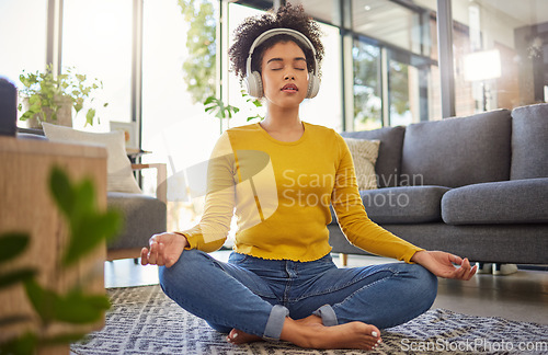 Image of Meditation, headphones and woman in home wellness, mental health or yoga podcast in living room. Music, streaming and african person meditate, holistic exercise and peace or lotus on audio technology