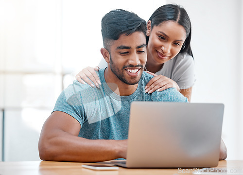 Image of Couple, laptop and Indian man in a home with online shopping and ecommerce app with wife support. Mockup, young people and happiness from promotion email in a house at desk with woman supporting