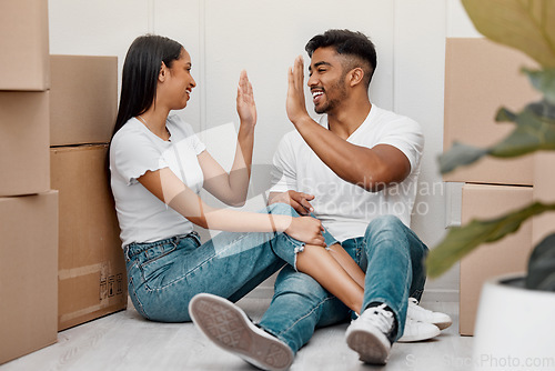 Image of Box, celebration and couple high five in new home excited for property, apartment and real estate investment, Relationship, house and man and woman celebrate with smile, boxes and happy on moving day