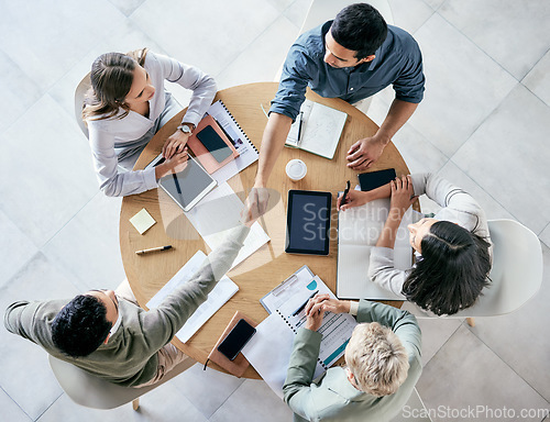 Image of Meeting, handshake and overhead with a business team sitting around a table in the office at work. Partnership, thank you and welcome with male colleagues shaking hands in agreement of a b2b deal