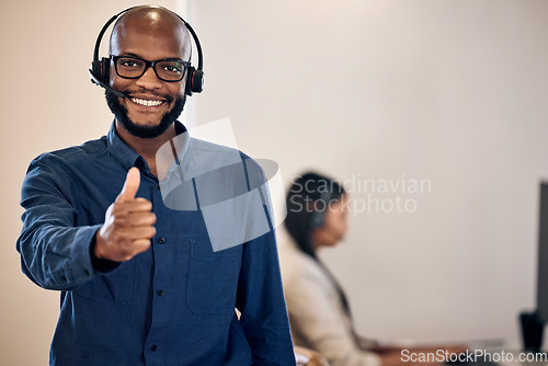 Image of Call center, thumbs up and a man smile for customer service, crm or telemarketing support. Black person, consultant or agent with headset and yes emoji or hand sign for sales, contact us or help desk