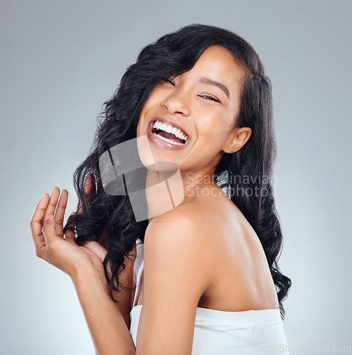 Image of Hair care, laughing and portrait of a woman with beauty isolated on a grey background in studio. Happy, smile and a young girl with a curly hairstyle, confidence and feminine with curls on a backdrop