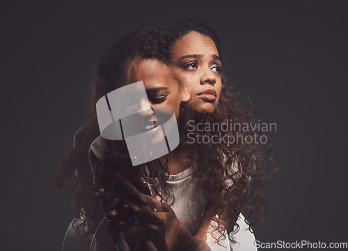 Image of Depression, mental health and woman in studio with stress, identity crisis or bipolar disorder. Horror, psycho and female person with trauma or anxiety browsing on a phone by a dark black background.