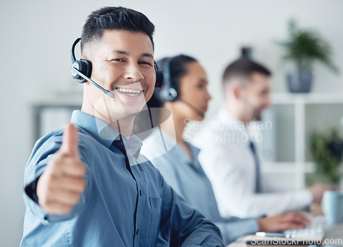 Image of Man at callcenter, thumbs up in portrait and CRM, communication of support and agreement emoji. Contact us, customer service and tech, male agent with headset and smile, success and yes hand gesture