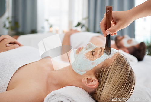 Image of Hand, brush and mask with a couple in a spa to relax on a massage table at a luxury resort together. Wellness, skincare and face treatment with a woman customer waiting for a facial from a masseuse