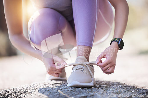 Image of Woman, hands and tie shoes for running, exercise or workout on asphalt road or street outdoors. Hand of female person or runner tying shoe getting ready for walk, run or fitness exercising in nature