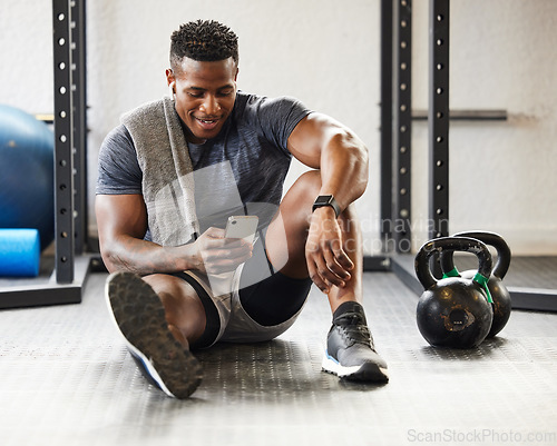 Image of Fitness, phone and black man typing in gym on break after exercise, training or workout. Athlete, smartphone and happy African male person on sports app, networking or social media, email and relax.