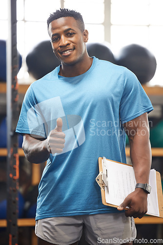 Image of Thumbs up, portrait and fitness man in gym, clipboard and checklist for workout results, progress and like, yes or okay hand. African person, athlete or bodybuilder paperwork and thank you sign