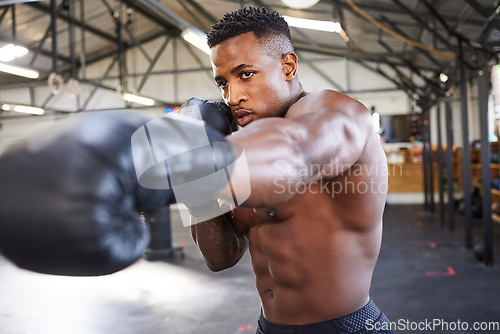 Image of African man, boxing and punching in gym for fitness, focus or training for growth, goal and health for competition. African guy, boxer and gloves for exercise, wellness or martial arts club for sport