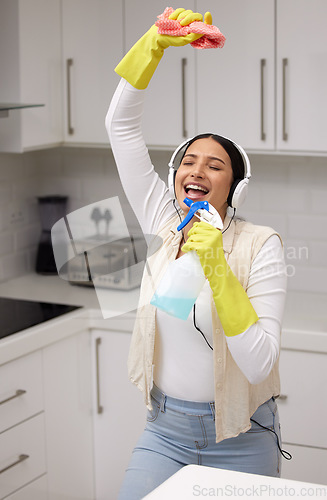 Image of Woman with headphones, singing while cleaning and chemical bottle as mic with fun and music, hygiene and house work. Young female cleaner, housekeeping and enjoy listening to radio, dancing and clean