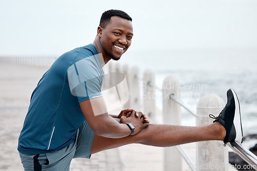 Image of Stretching, fitness and portrait of black man by ocean for exercise, marathon training and running. Sports, nature and happy male person stretch legs for warm up, cardio workout and wellness by sea