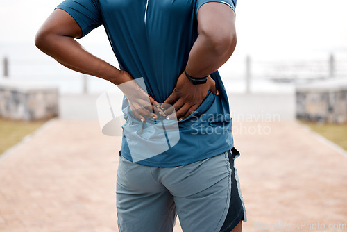 Image of Man, fitness and back pain after workout, cardio exercise or running and training outdoors. Rear view of male person, athlete or runner with sore spine, injury or ache and bone inflammation in nature