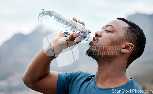 Image of Drinking water, fitness and black man in nature for exercise, marathon training and running outdoors. Sports, workout and thirsty male person rest to drink liquid for hydration, wellness and health