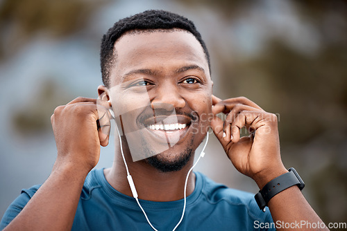 Image of Black man, earphones and listening to music with smile in workout, exercise or cardio training in nature. Happy African male person, athlete or runner smiling for audio sound track or outdoor fitness