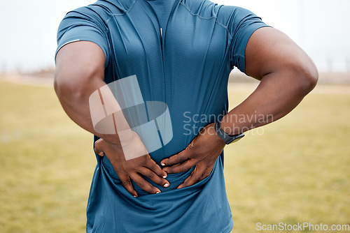 Image of Man, fitness and back pain after running exercise, cardio workout or training on grass field outdoors. Rear view of male person, athlete or runner with sore spine, injury or bone inflammation outside