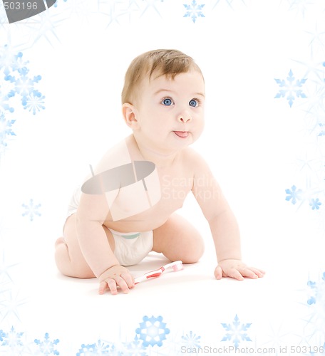 Image of baby boy in diaper with toothbrush sticking tongue out
