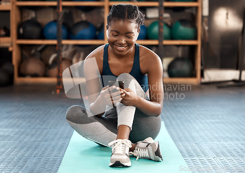 Image of Happy black woman, fitness and phone for social media, communication or networking at the gym. African female person or athlete typing, texting or chatting on mobile smartphone after workout exercise
