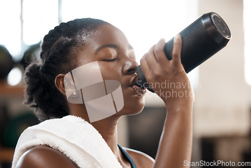 Image of Black woman, fitness and drinking water at gym for sustainability, hydration or thirst after workout exercise. Thirsty African female person with drink for refreshment after cardio training indoors