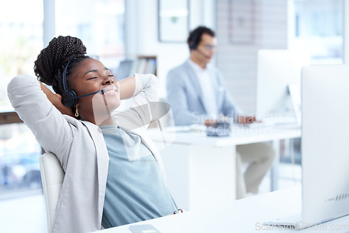 Image of Call center, woman and relax with headset and computer on desk for telemarketing or customer service. Black female on break with smile for complete, finish or productivity in crm, support or sales