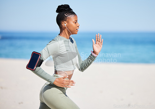 Image of Fitness, beach and woman running, listening to music, exercise podcast or training, cardio and health technology. Ocean, focus and african person, runner or athlete workout, training and phone audio