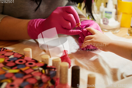 Image of Little girl is getting manicure in beauty salon, close-up.