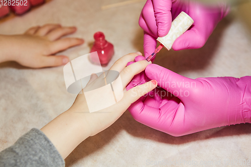 Image of Little girl is getting manicure in beauty salon, close-up.