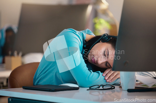 Image of Call center, customer service and a woman consultant sleeping at her desk in the office late at night. Exhausted, overworked and a tired female employee asleep while consulting for crm or sales