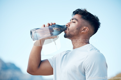 Image of Man, fitness and drinking water in nature exercise, cardio workout or running for sustainability outdoors. Thirsty male person, athlete or runner with drink for hydration, rest or break on mountain