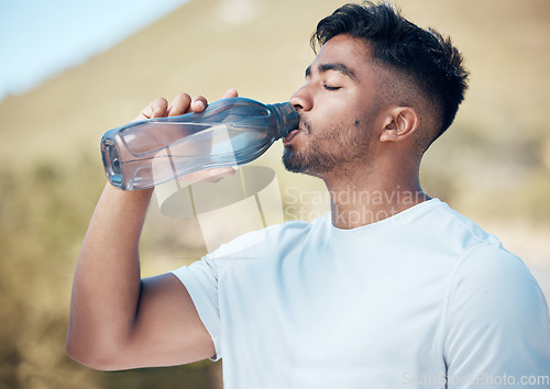 Image of Man, fitness and drinking water in nature for sustainability, running exercise or cardio workout outdoors. Thirsty male person, athlete or runner with drink for hydration, rest or break on mountain