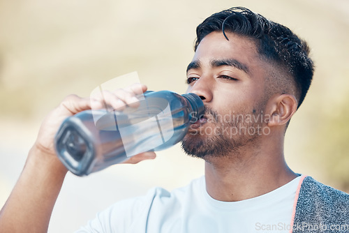 Image of Man, fitness and drinking water in nature for hydration, running exercise or cardio workout outdoors. Thirsty male person, athlete or runner with drink for sustainability, rest or break on mountain