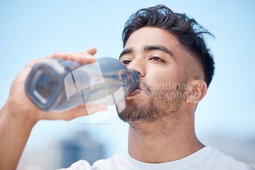 Image of Man, fitness and drinking water in city for sustainability after running exercise, workout or training outdoors. Thirsty male person, athlete or runner with drink for hydration, rest or break in town