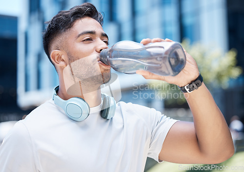Image of Man, fitness and drinking water in city exercise, cardio workout or running for sustainability outdoors. Thirsty male person, athlete or runner with drink for hydration, rest or break in urban town