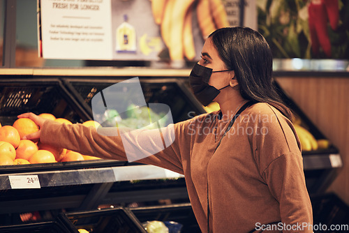 Image of Grocery shopping, woman and fruit at a retail shop, market and store for groceries with mask. Health, virus safety and female person with orange and healthy food purchase in a supermarket at shelf