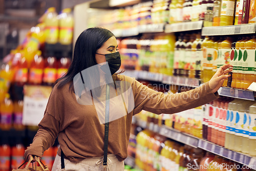 Image of Grocery shopping, woman and juice at a shop, market and store for groceries sale with mask. Health, virus safety and female person with orange and healthy drink purchase in a supermarket at shelf