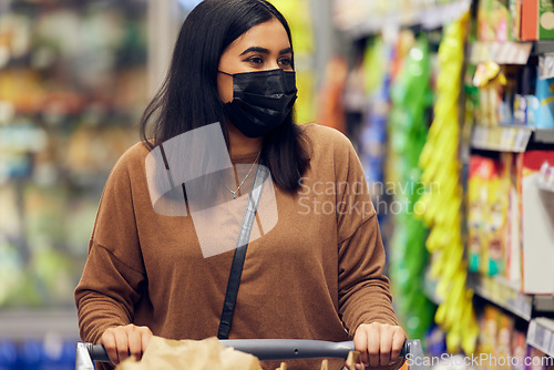 Image of Grocery shopping, woman and cart at a retail shop, market and store for groceries with mask. Health, virus safety and female person with choice and food browse for purchase in a supermarket at shelf