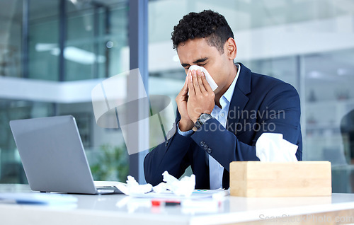 Image of Sick, sinus and business man with an allergy blowing nose with tissue in an office with a cold or virus infection. Company, worker and young person or employee sneeze at a table or desk while working