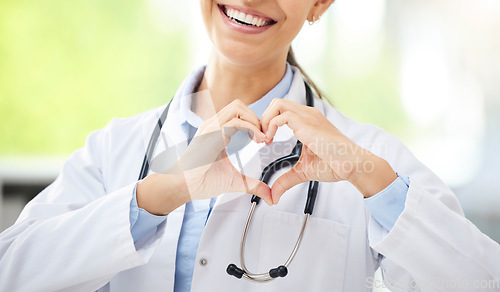 Image of Love, woman doctor with heart sign and with smile at a hospital for healthcare. Medication or health wellness, nurse and support hand emoji with a female surgeon with stethoscope at a clinic.