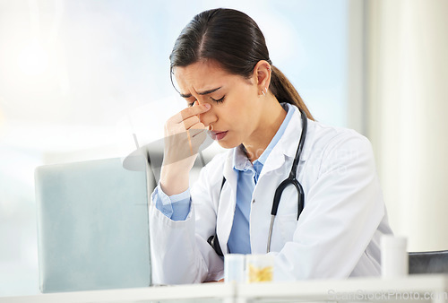 Image of Mental health, woman doctor sad and with laptop at her desk in a modern office with a lens flare. Depression or headache, problem or burnout and female nurse or surgeon fatigue at her workstation