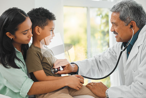 Image of Doctor checking a kid patient with stethoscope on a sofa for home medicare consultation. Healthcare, pediatrician and mother sitting with her boy child for male medical worker to listen to breathing.