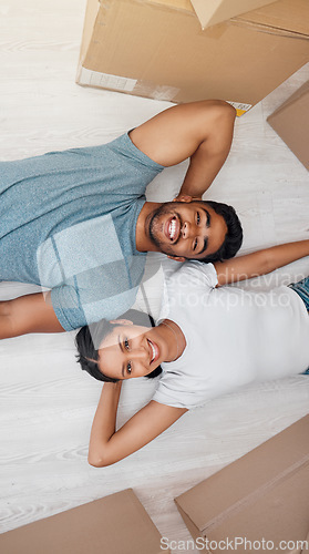 Image of Top view, home and couple with boxes, real estate and excited on the floor, living room and mortgage. Portrait, man and woman on the ground, cardboard and relationship with property and apartment