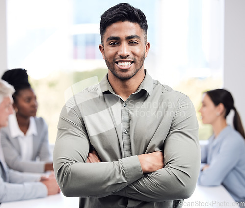 Image of Portrait, smile and a business man arms crossed in the boardroom with his team planning in the background. Leadership, workshop and confidence with a happy young male employee standing in the office