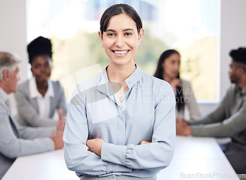 Image of Portrait, smile and a business woman arms crossed in a boardroom with her team planning in the background. Leadership, workshop and confidence with a happy young female employee standing in an office