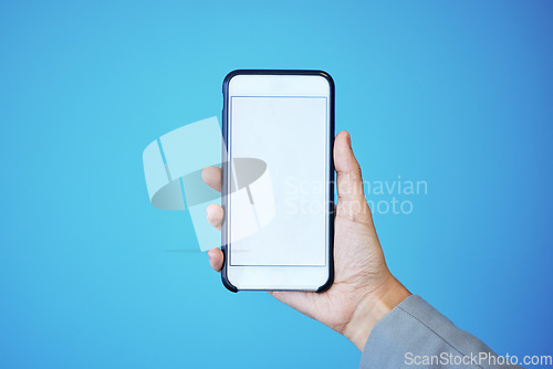 Image of Person, phone and hand with mockup screen for advertising or marketing against a blue studio background. Hands, mobile smartphone or app with mock up, copy space or display for brand advertisement