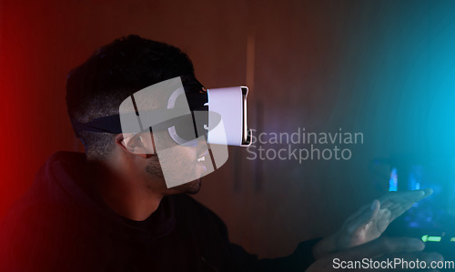 Image of Man in dark room, video game and virtual reality, online streaming with gaming, metaverse and esports. Cyber digital world, male streamer and future technology with games, VR goggles and simulation