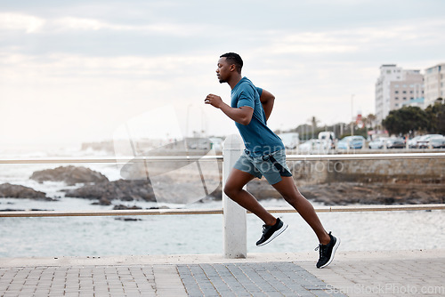 Image of Black man, runner and exercise outdoor on beach promenade for fitness, training or cardio workout. African athlete, person and running at sea for performance, health and wellness in nature with focus