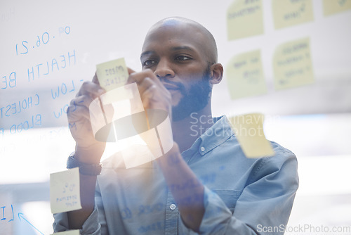 Image of Brainstorming, writing and business man on glass board for planning, schedule and scrum or agile solution. Thinking, ideas and focus of African person on window sticky notes, job priority or reminder