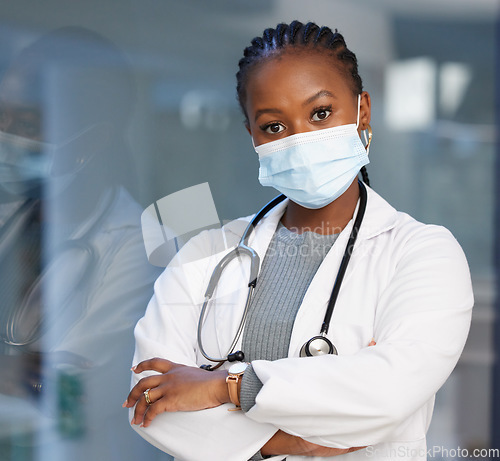 Image of Portrait, virus and arms crossed with a doctor black woman in the hospital wearing a mask for safety. Medical, healthcare and insurance with a female medicine professional you can trust in a clinic