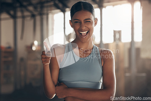 Image of Woman in gym, thumbs up with wink in portrait, like fitness with emoji and health goals with sport and mockup space. Hand gesture, yes and motivation with Indian female athlete at exercise studio